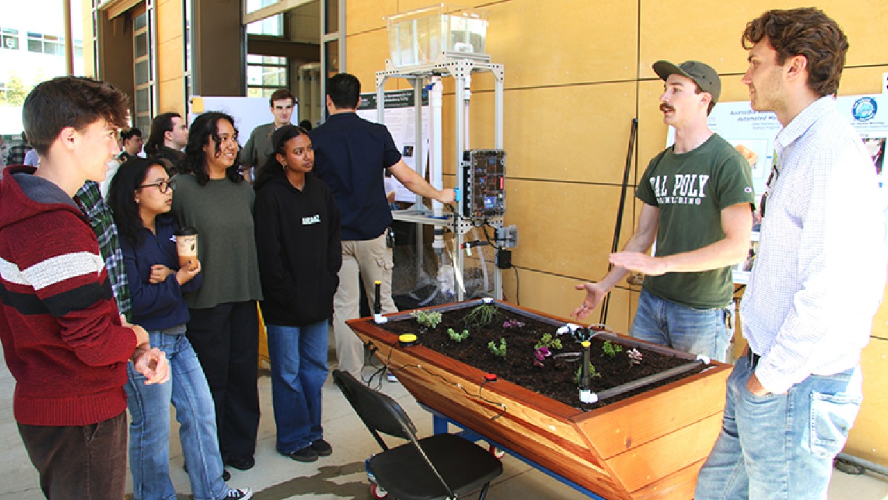 Cal Poly mechanical engineering seniors Matthew Podgorski, right, and Gabe Haarberg, second from right, explain the accessible garden box during Project Expo. The team later installed the project in Heather McColley’s medically fragile classroom at Oceano Elementary School.