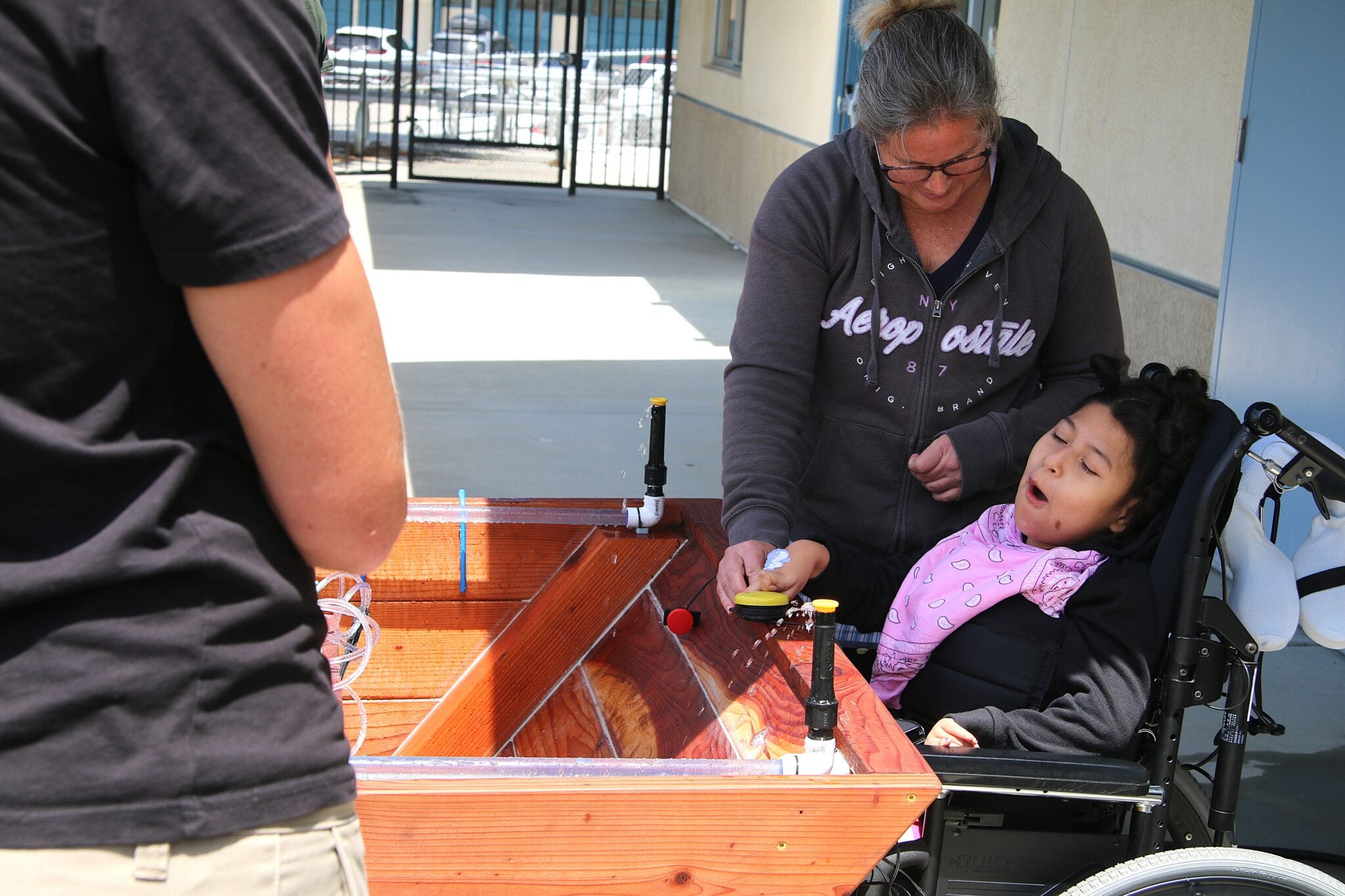 Heather McColley guides Marion as she presses a button on the garden box during the project’s first use at Oceano Elementary School. The box was designed to help students explore cause and effect through water movement. 