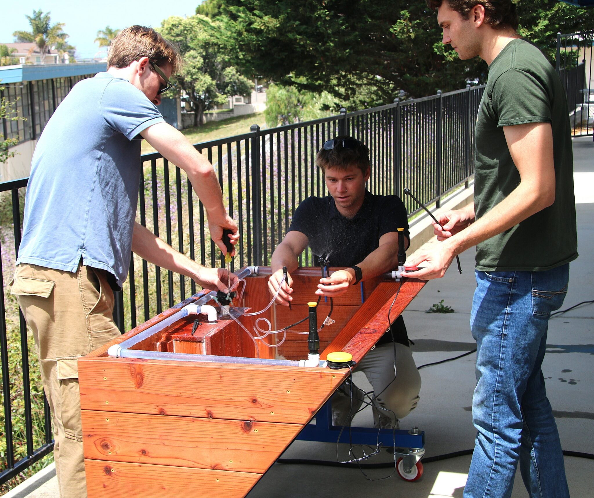 Garden box team members adjust the irrigation system during installation at Oceano Elementary School. The setup allows students to send water through clear tubing and into the planter. 