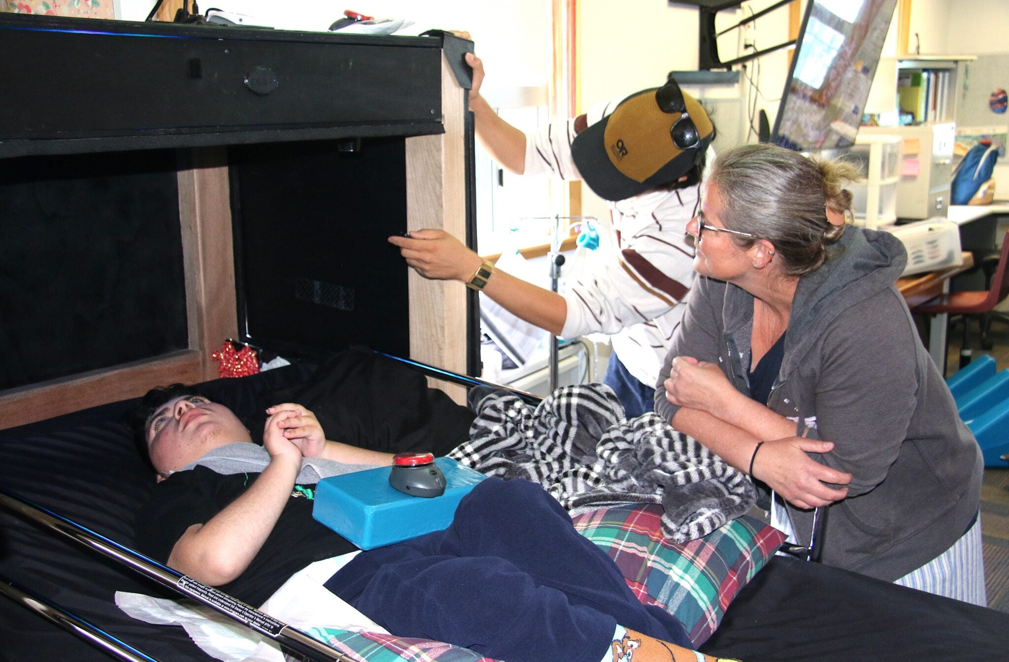 Marcus Kanenaga walks Heather McColley through the sensory den as Evan experiences the moving lights from a hospital bed in McColley’s classroom at Oceano Elementary School. 