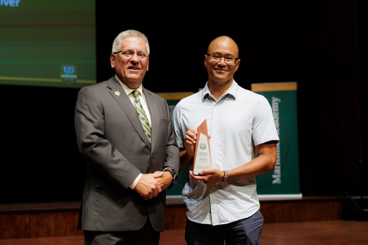 Professor holds award with president on stage