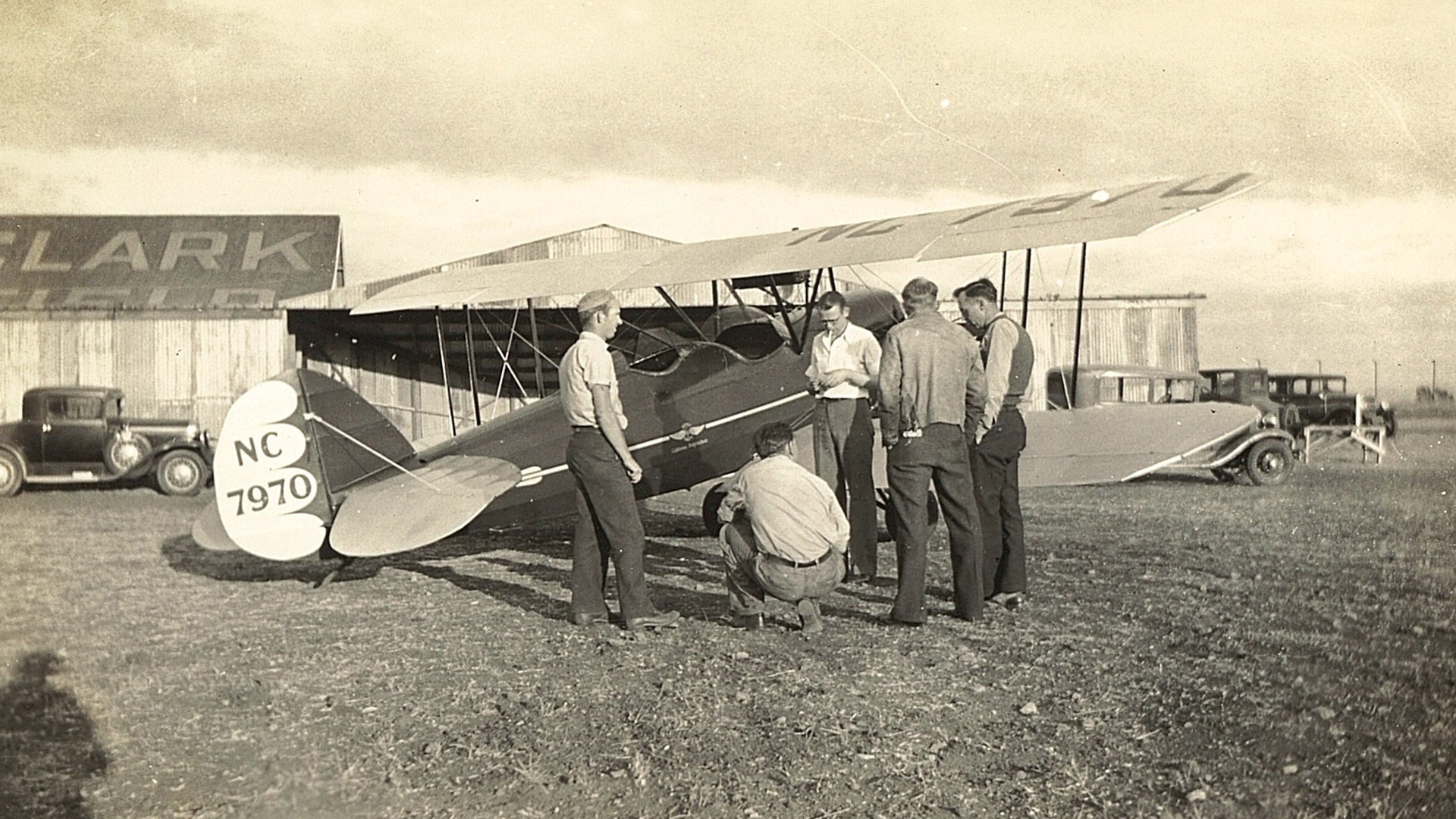 Cal Poly students confer beside a biplane at Clark Field in San Luis Obispo, reflecting the program’s early ties to flight.