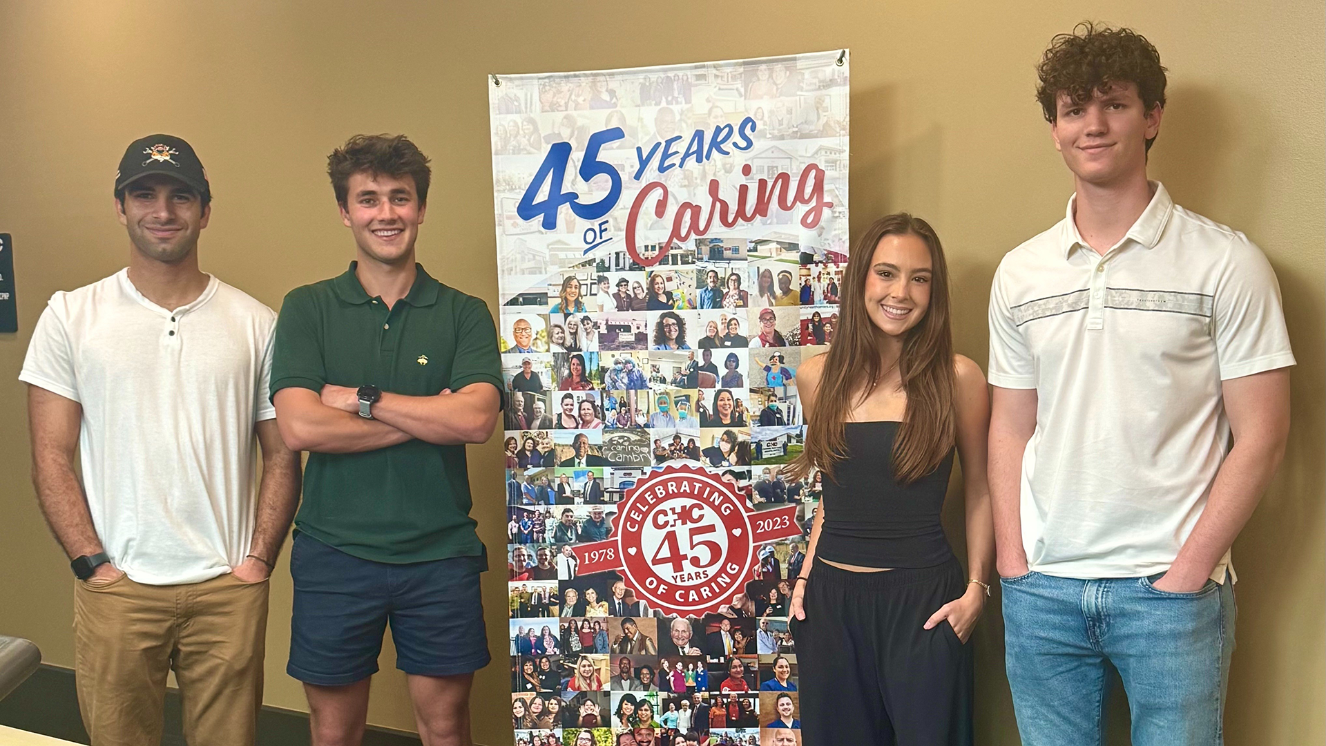 Students stand next to hospital sign featuring multiple photos
