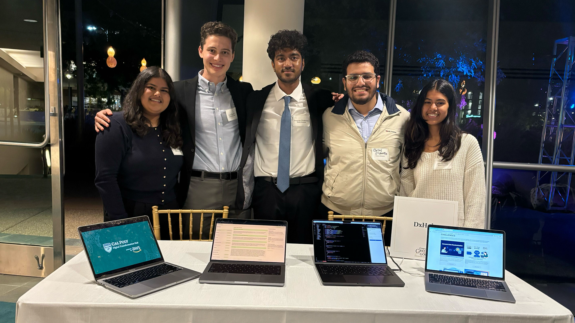 Group of students pose behind laptop computers
