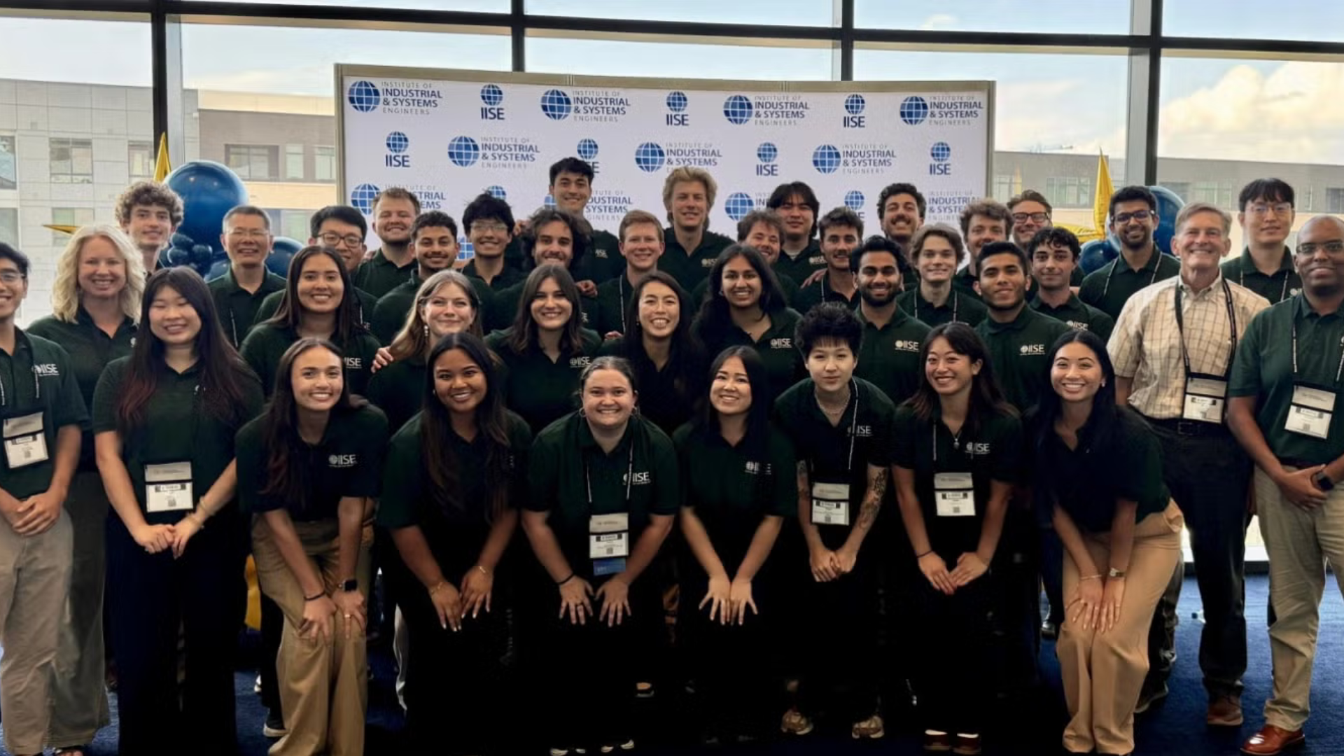 A group of students posing in front of a step-and-repeat at a conference