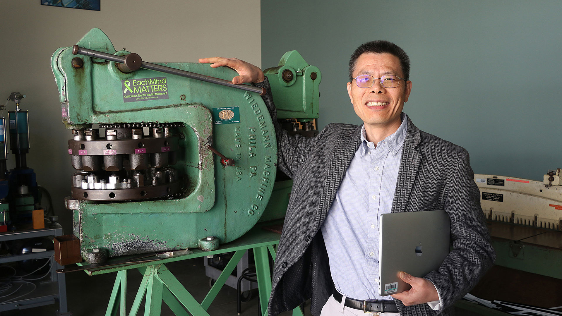 Professor stands next to machining tool