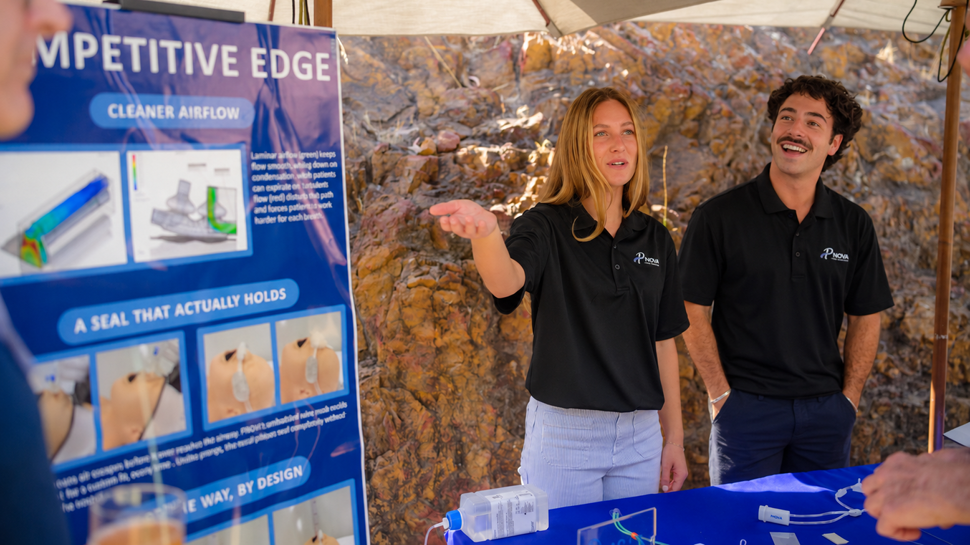 Students explain their poster to Demo Day attendees