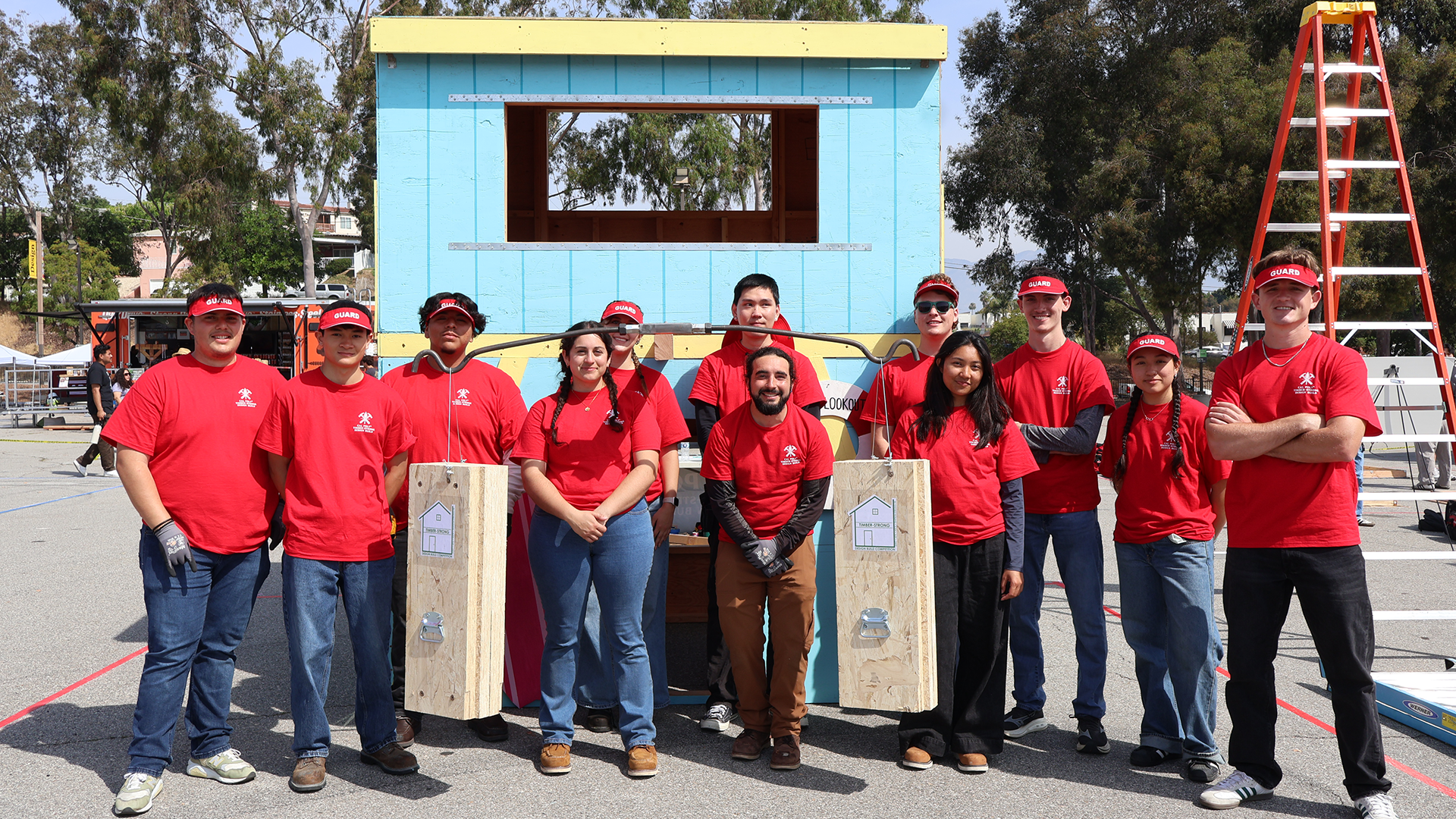 Students stand next to their completed timber structure
