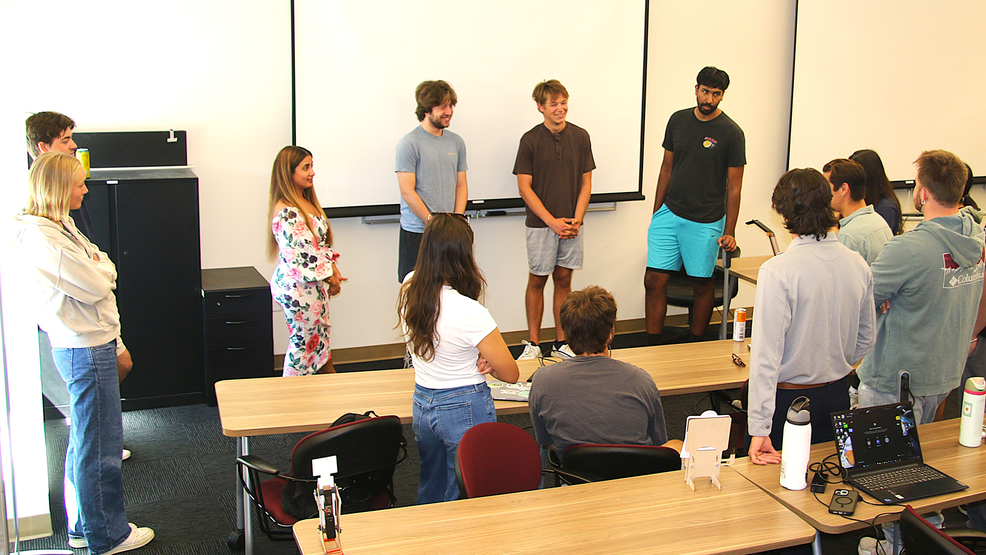 Students and professor gather in a circle to share progress 
