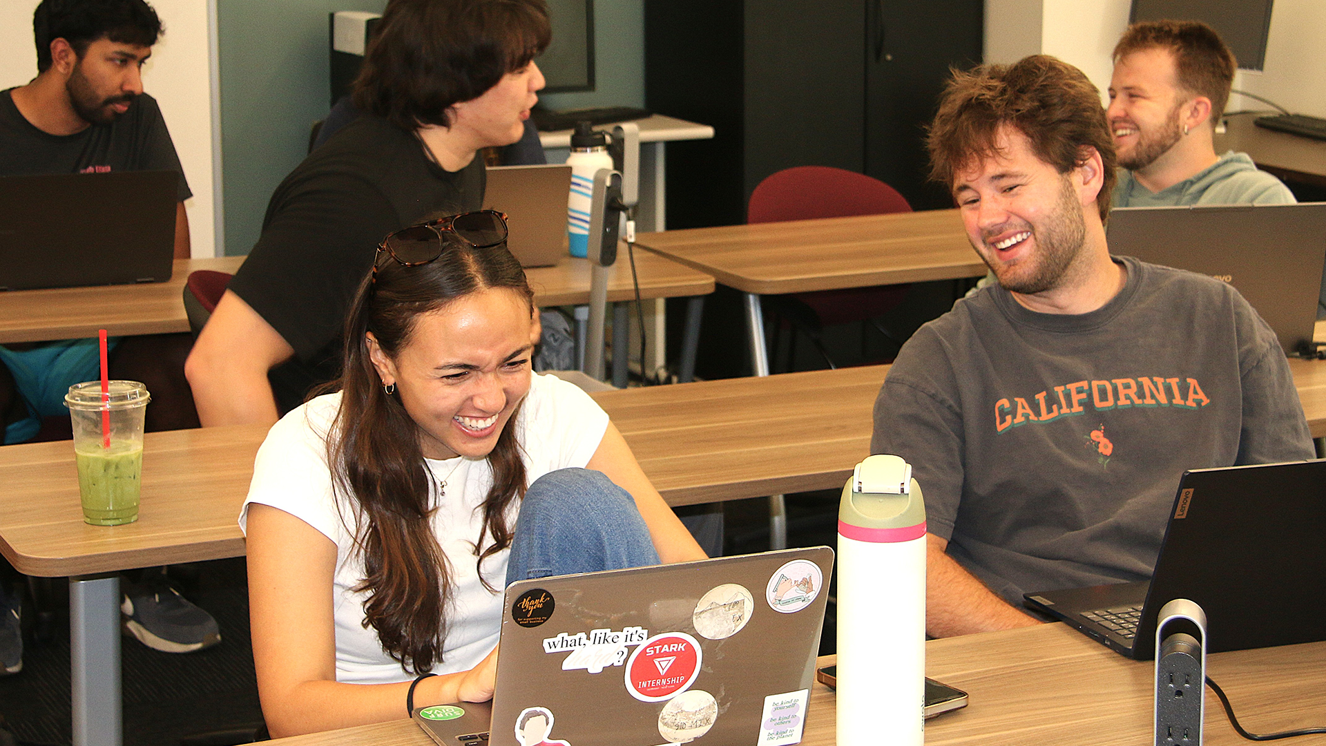 Students share a laugh while working on their laptops
