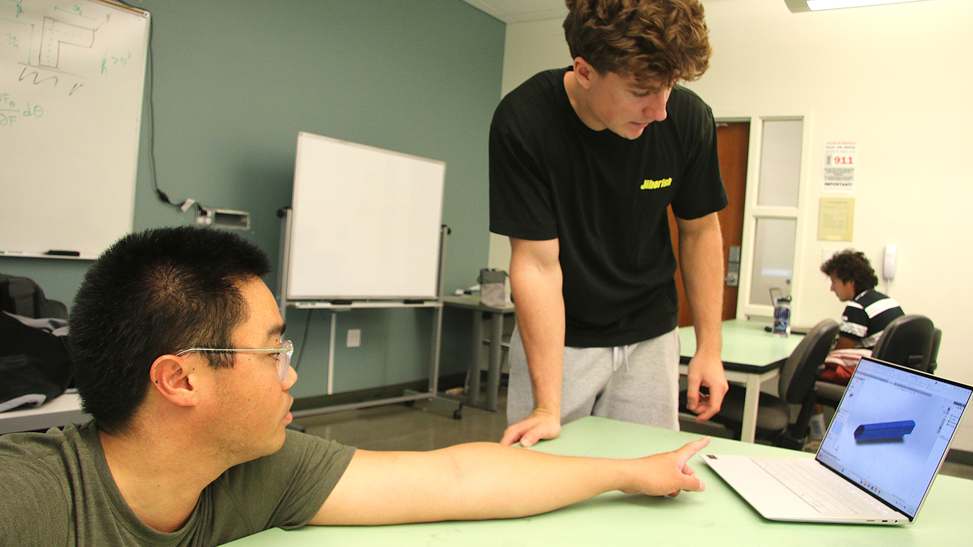 Lecturer works with student over a model on a laptop