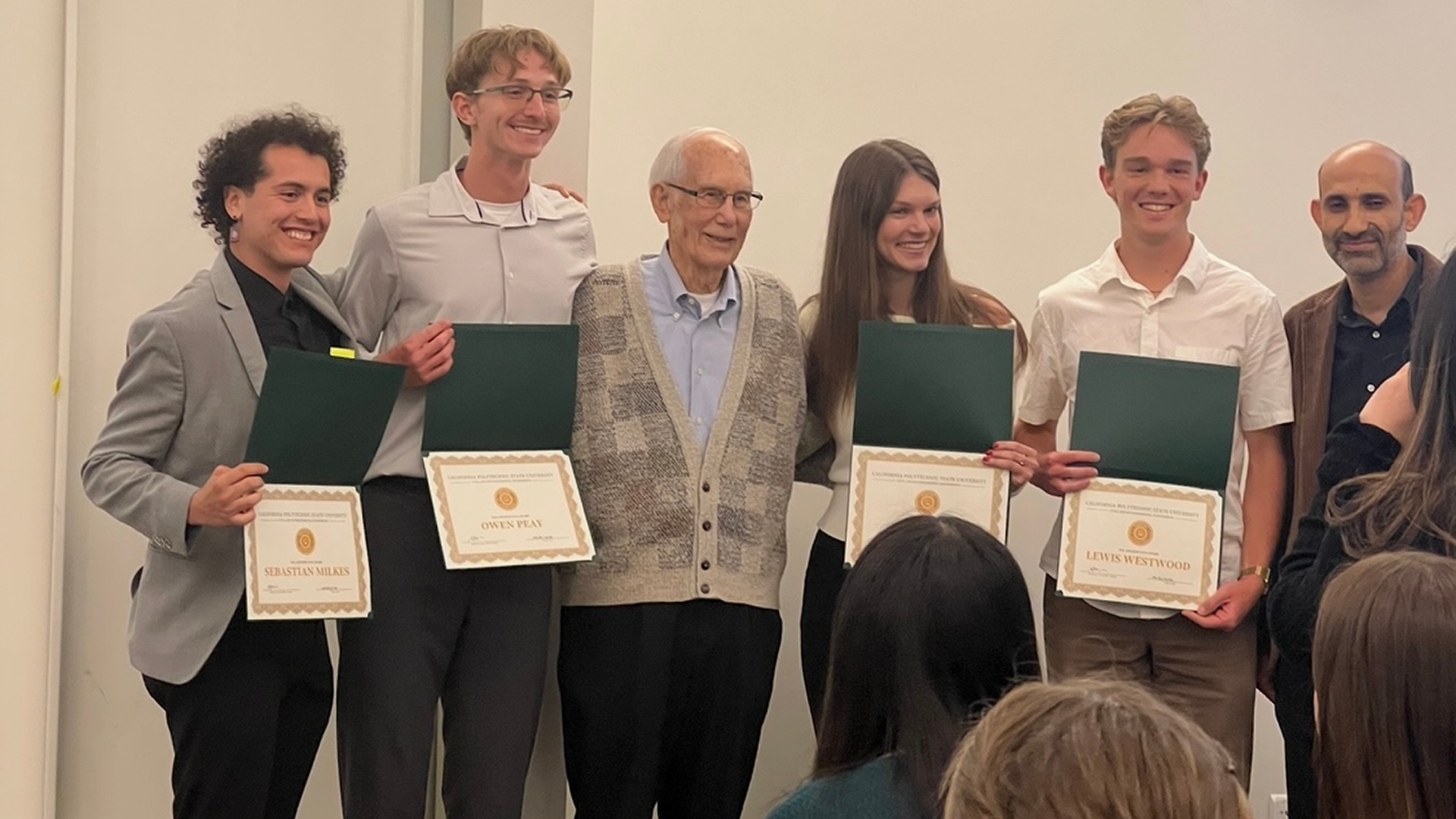 Students hold scholarship certificates with Hal Cota