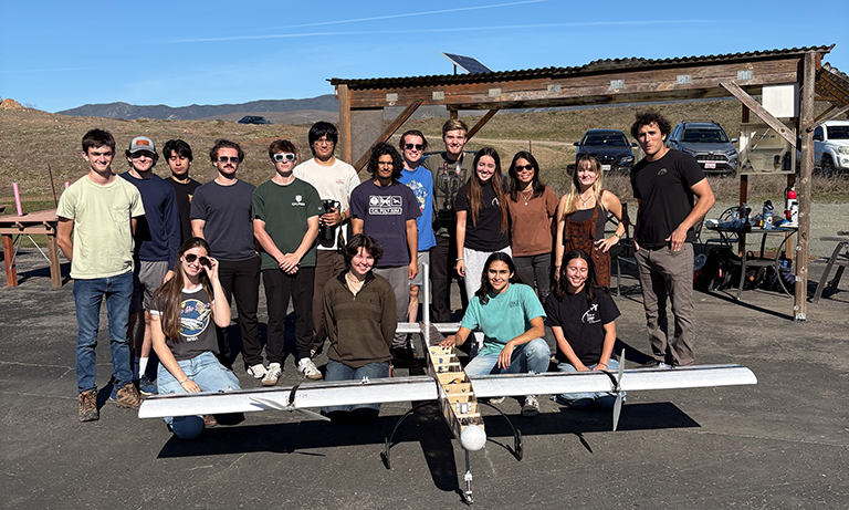 Members of club stand next to a prototype of their plane