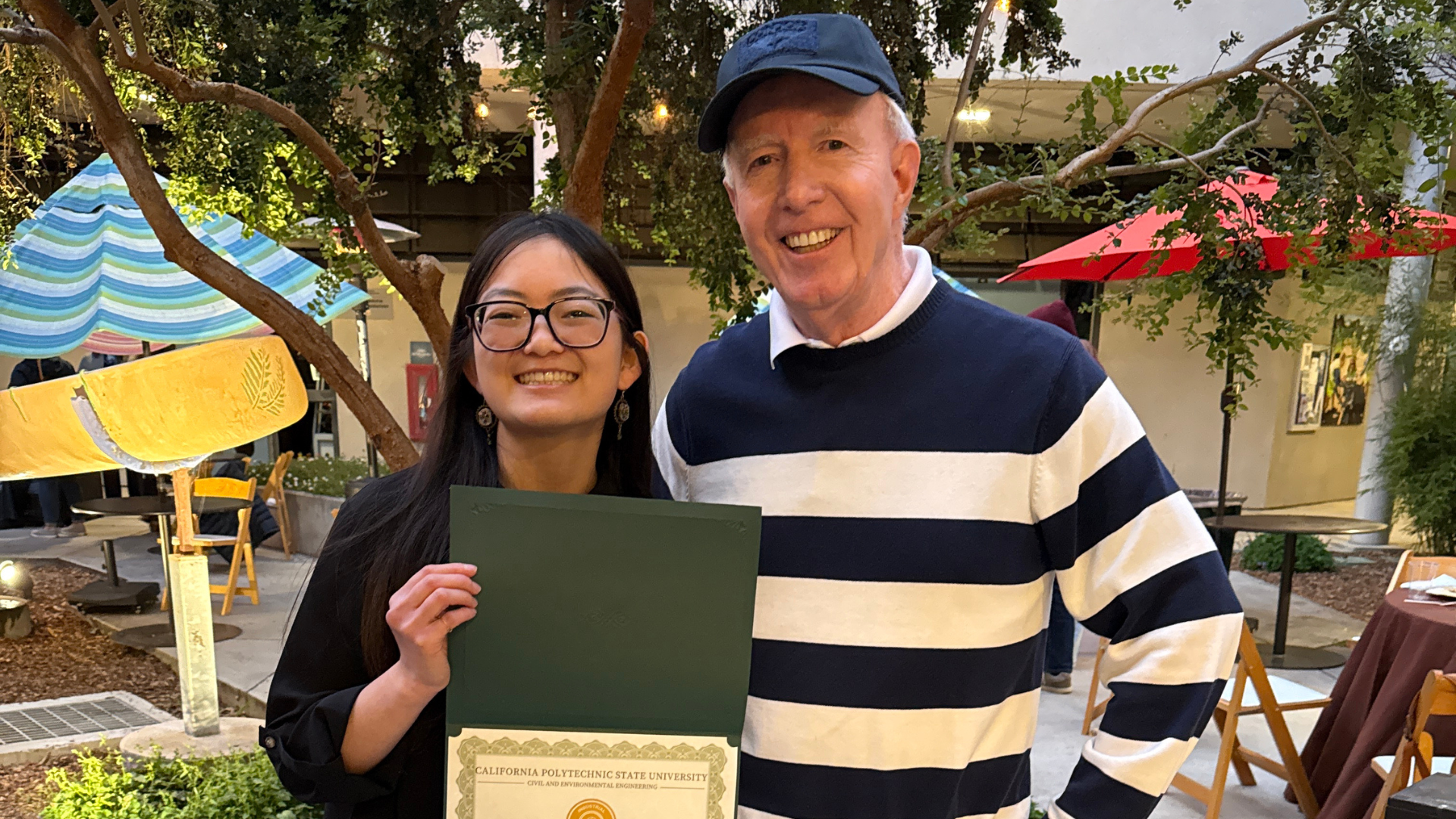 A student holding up a scholarship certificate alongside the scholarship donor