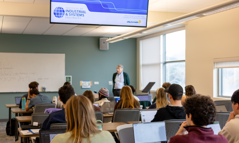 A group of people in a classroom looking at the speaker at the front of the class
