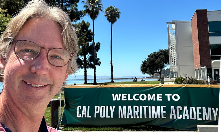 Mike Holden in front of a Cal Poly Maritime Academy sign