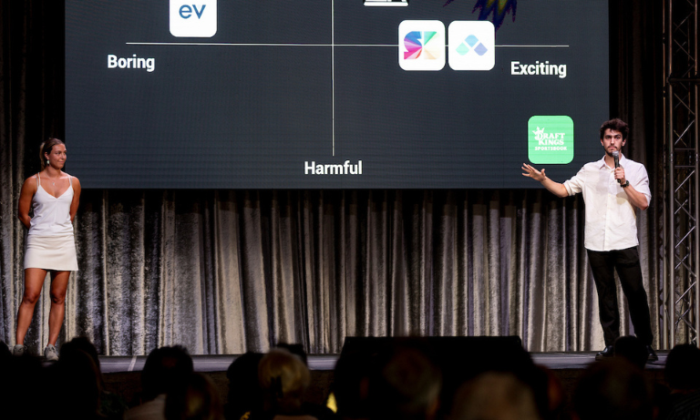 Two people standing on a stage presenting their project proposal to a crowd