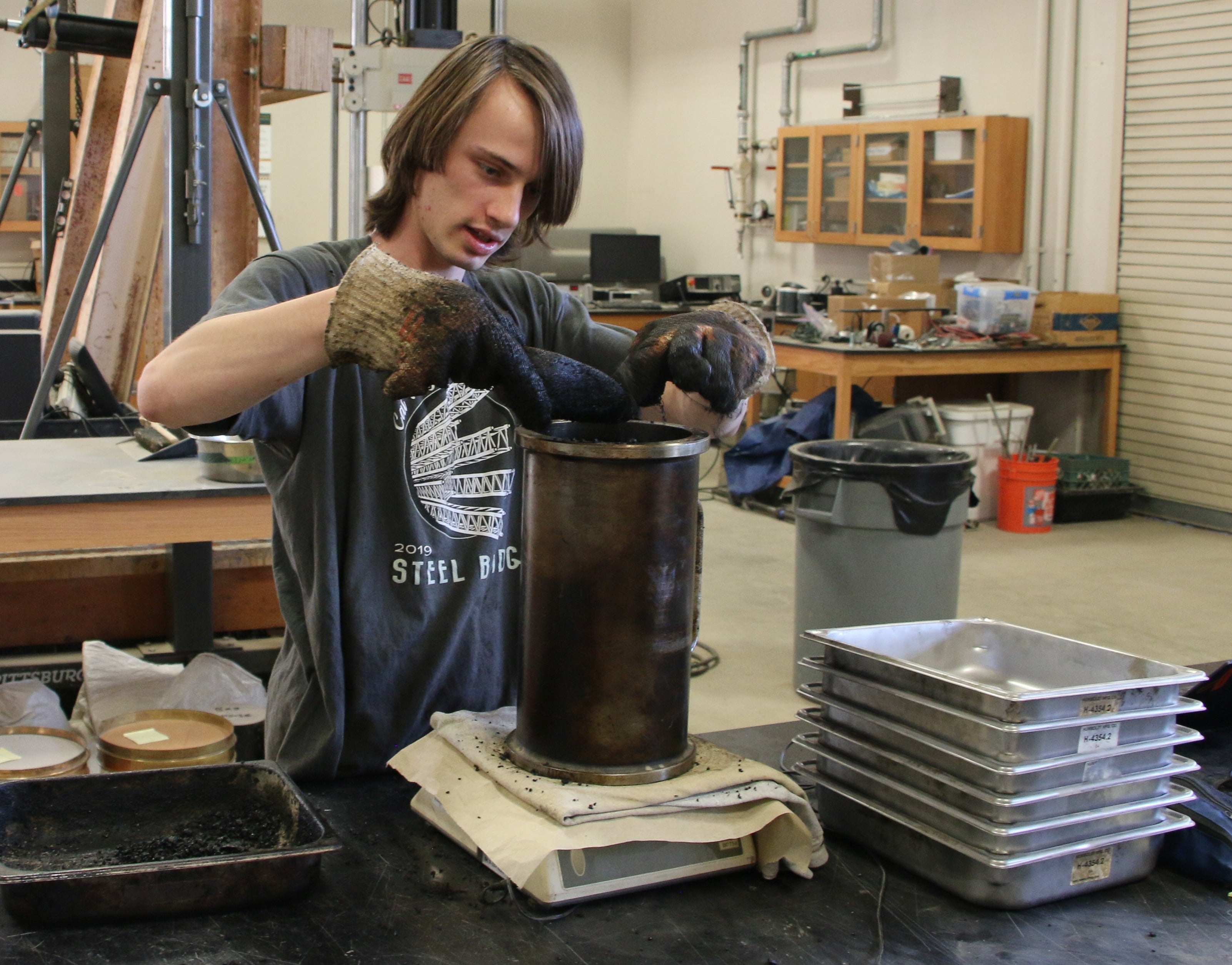 Student works in the Pavement Lab, weighing an asphalt puck