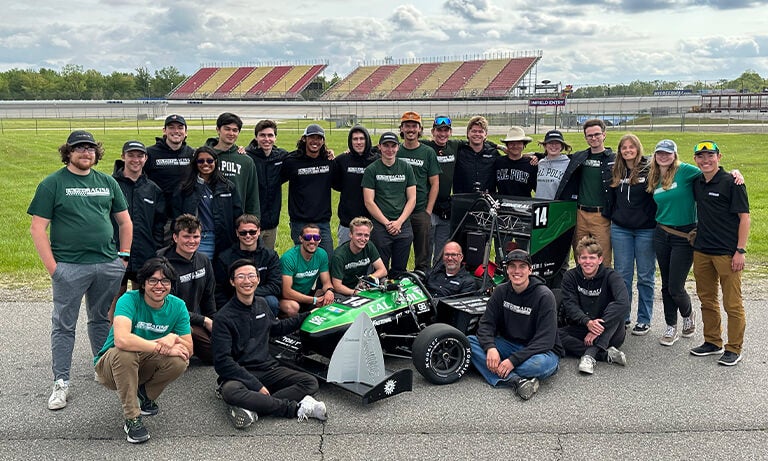 Cal Poly Racing Formula SAE team gathers around car on track