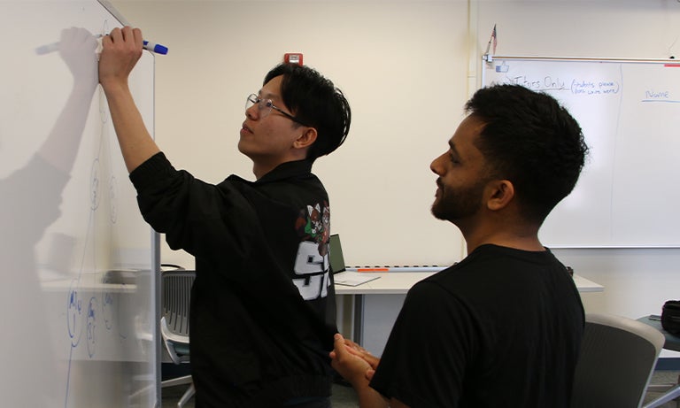 Tutors work out a problem-solving approach on the whiteboard
