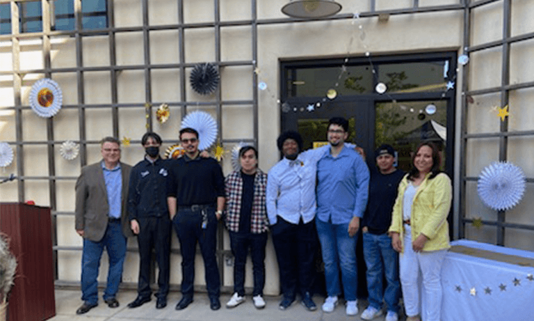 A group of students and mentors posing for a picture in front of celebration decorations