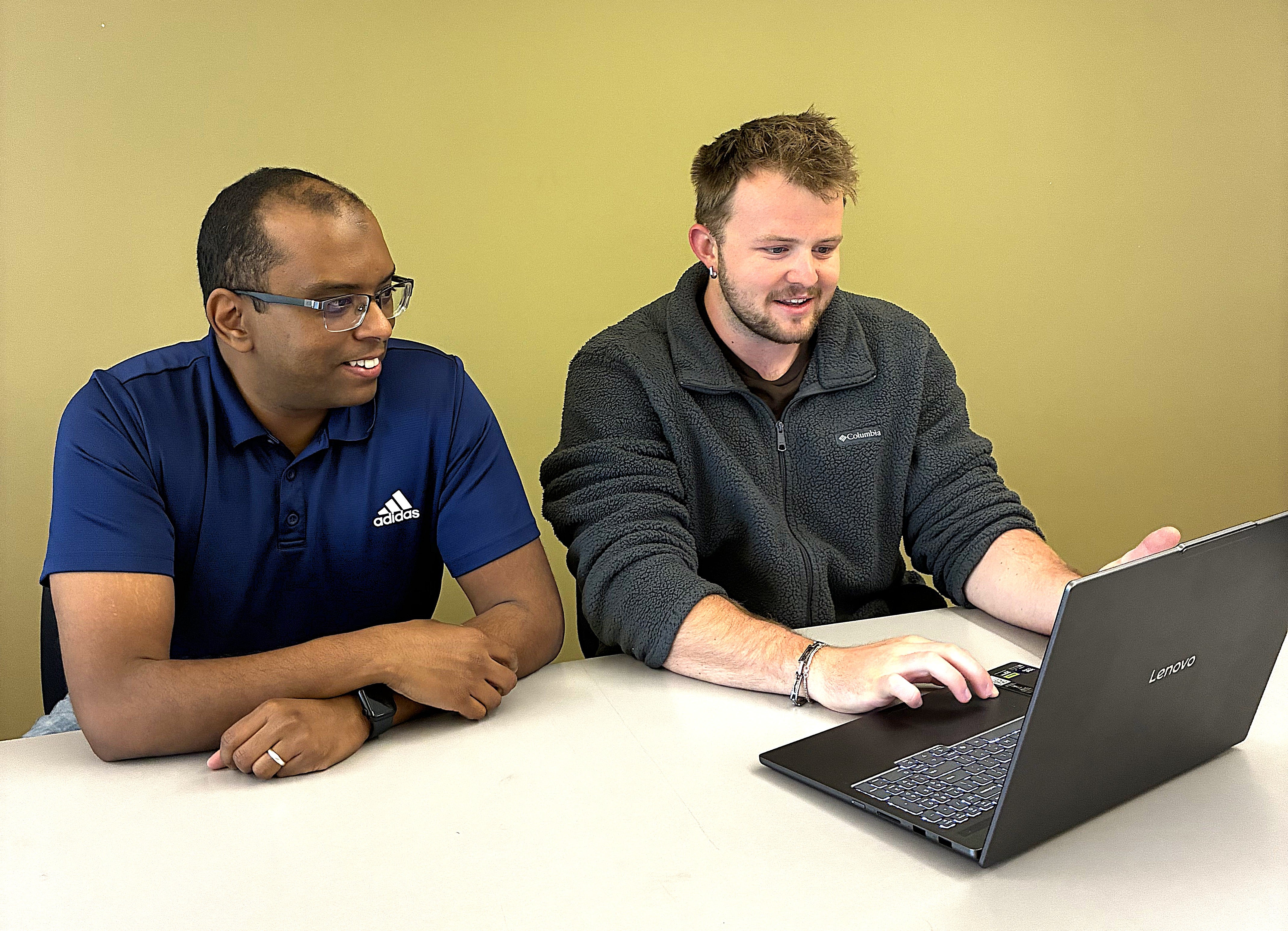 Student and professor work at laptop