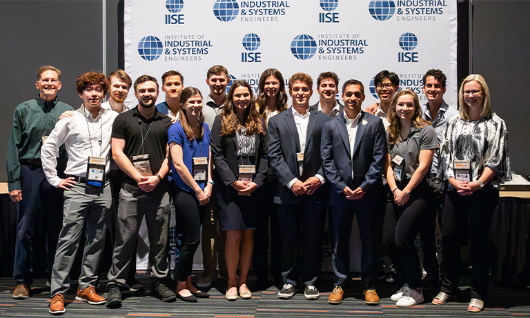 A group of people standing in front of a large event banner smiling