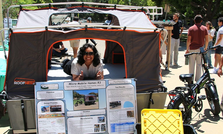Student gives a thumbs-up from inside a micromobile home
