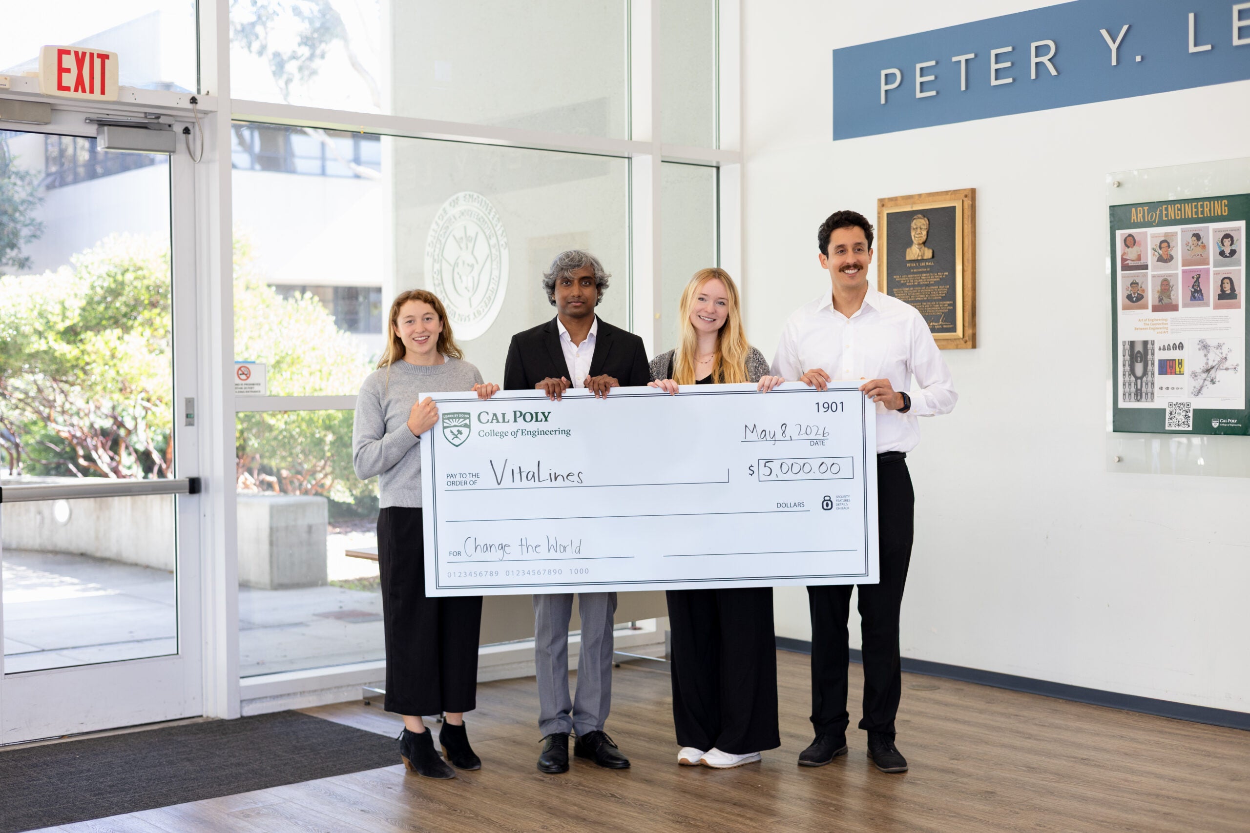 Four students holding a giant check