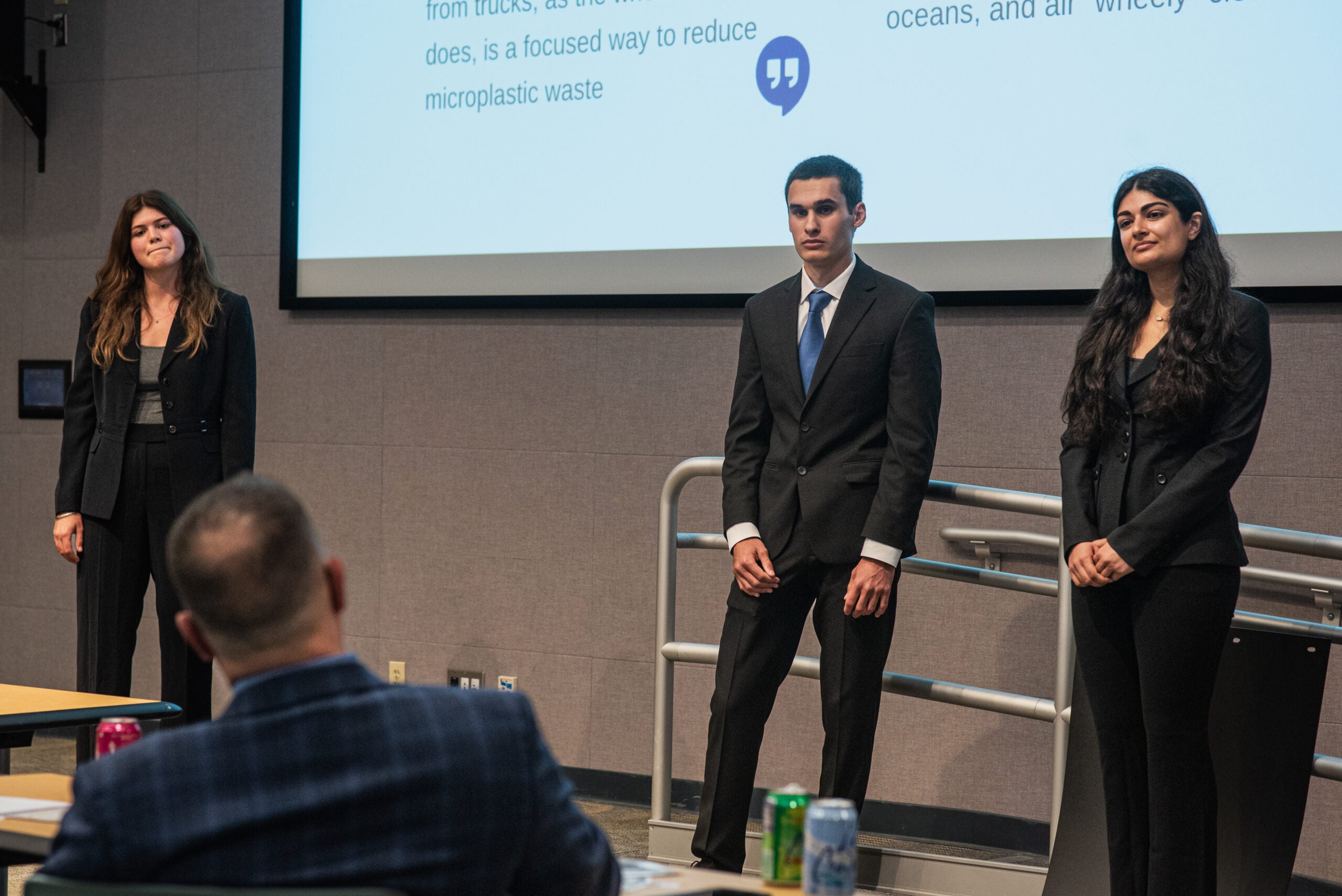 Three people on a stage giving a presentation