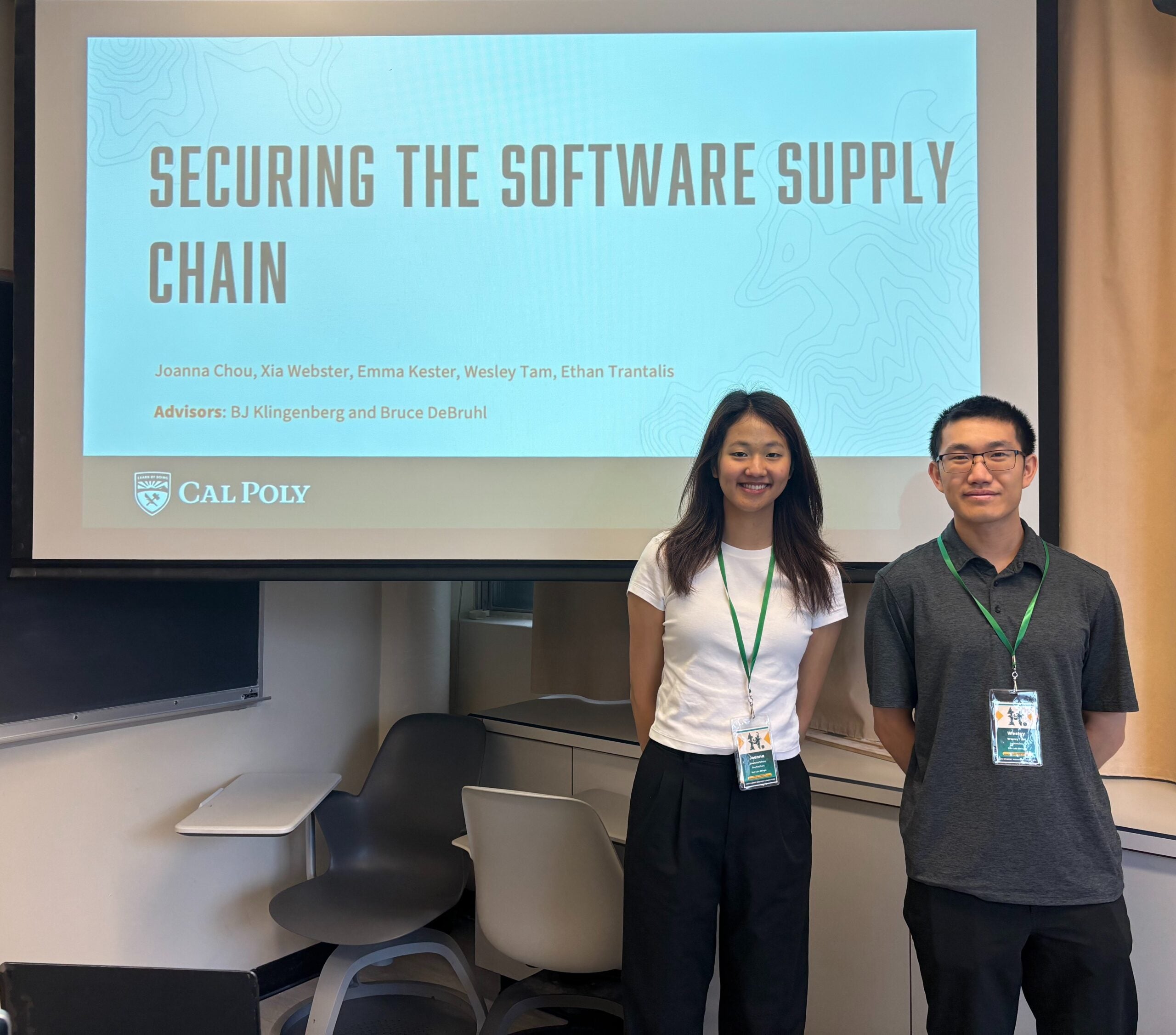 Joanna and Wesley stand in front of their presentation on screen 