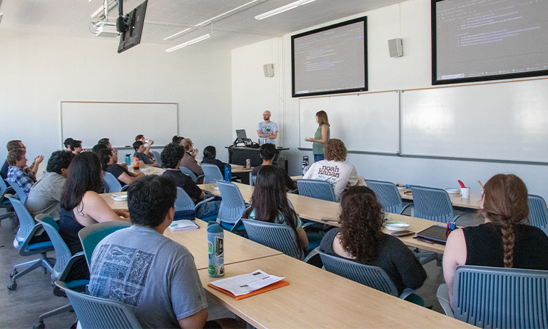 Students in a classroom focusing on the teachers at the front.