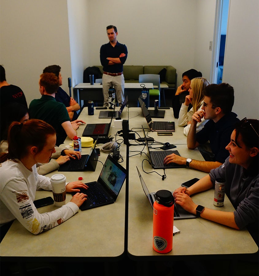 Professor helps students during class as they work on their laptops