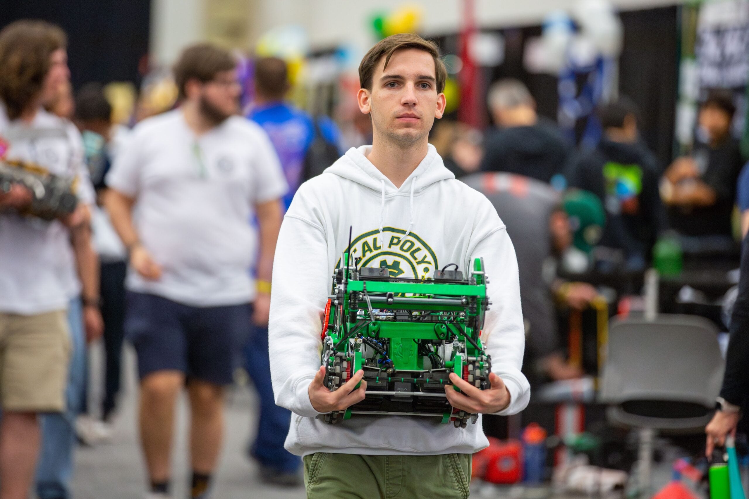 Project lead Garrett Schnack carries one of the Gear Slingers' robots through the convention center 