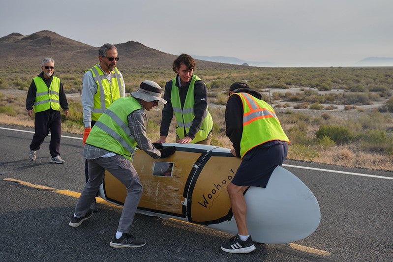 Volunteers and teammates hold the human-powered vehicle upright after run