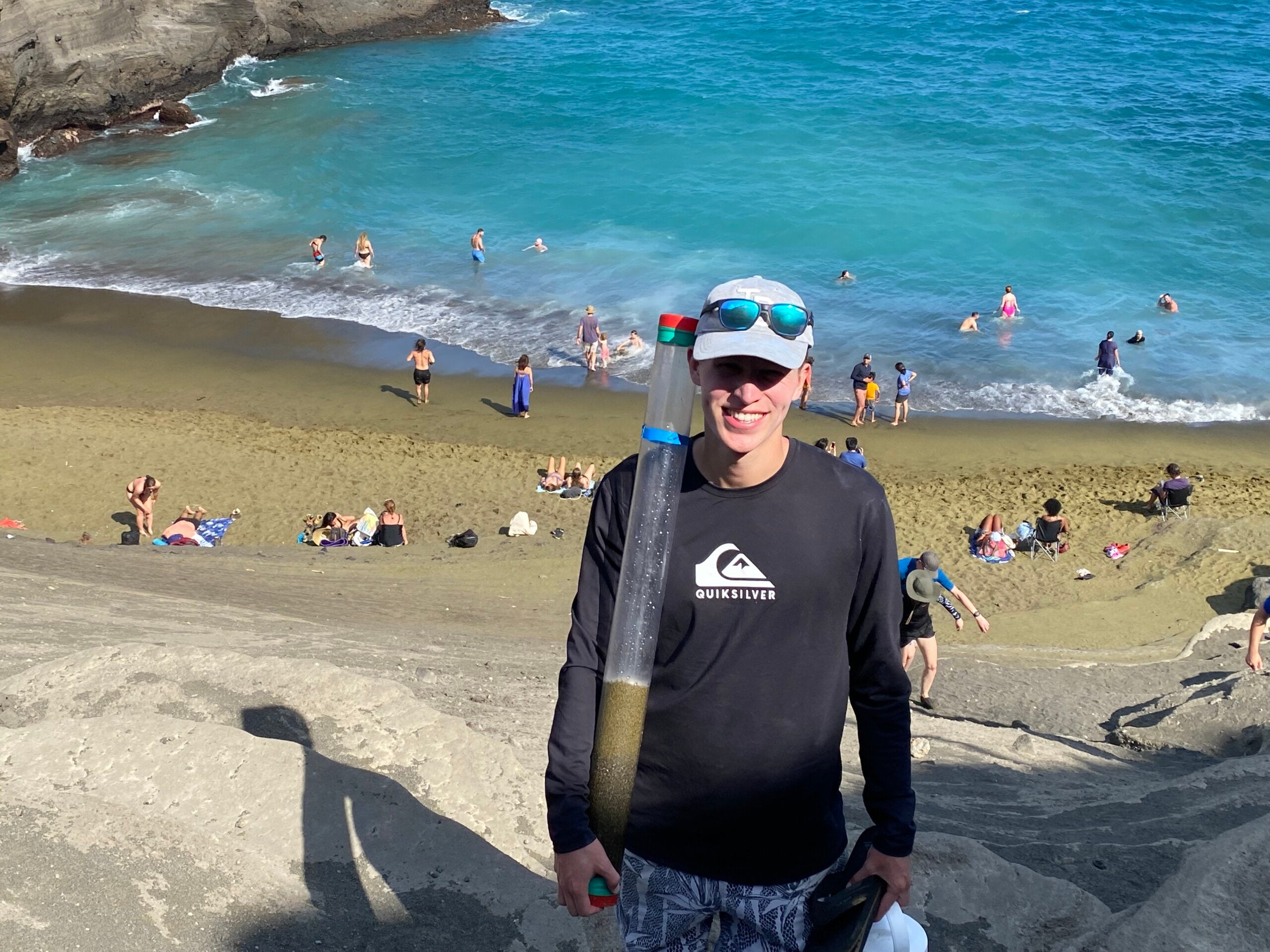 Cal Poly student has a sample of green sand during a research trip to Hawaii