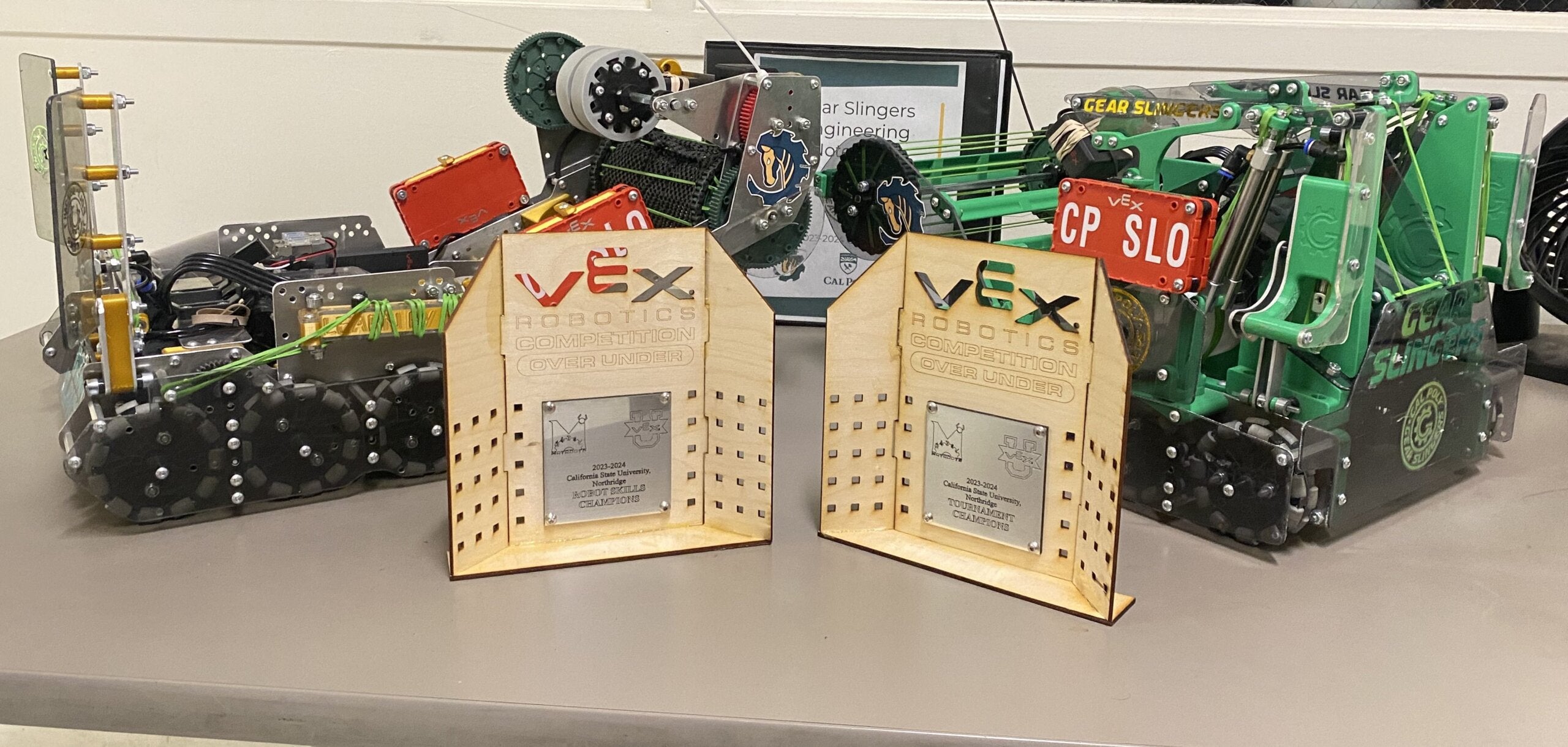 Toothless and Hiccup, the Gear Slingers' robots, are posed next to two trophies from a recent competition