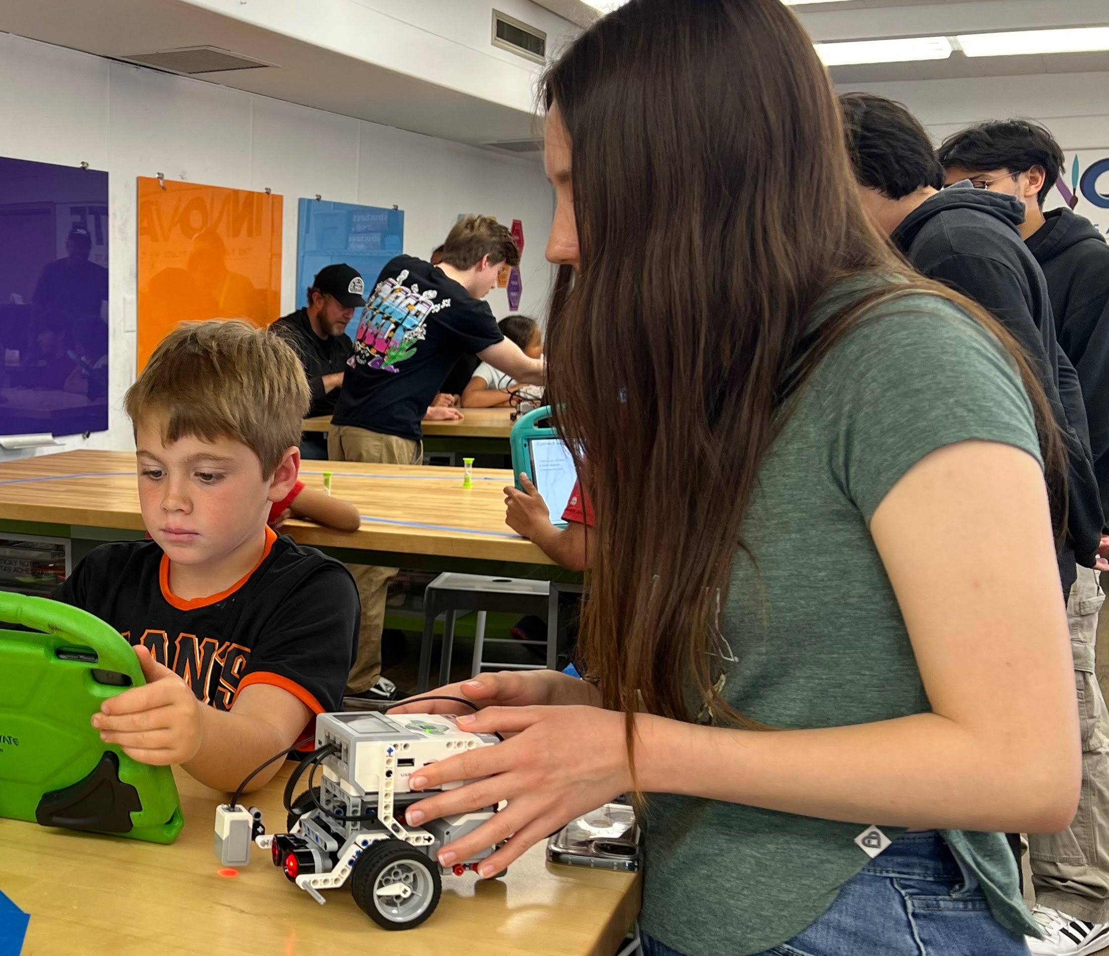A woman helping a young student with his project, while the student looks at his tablet