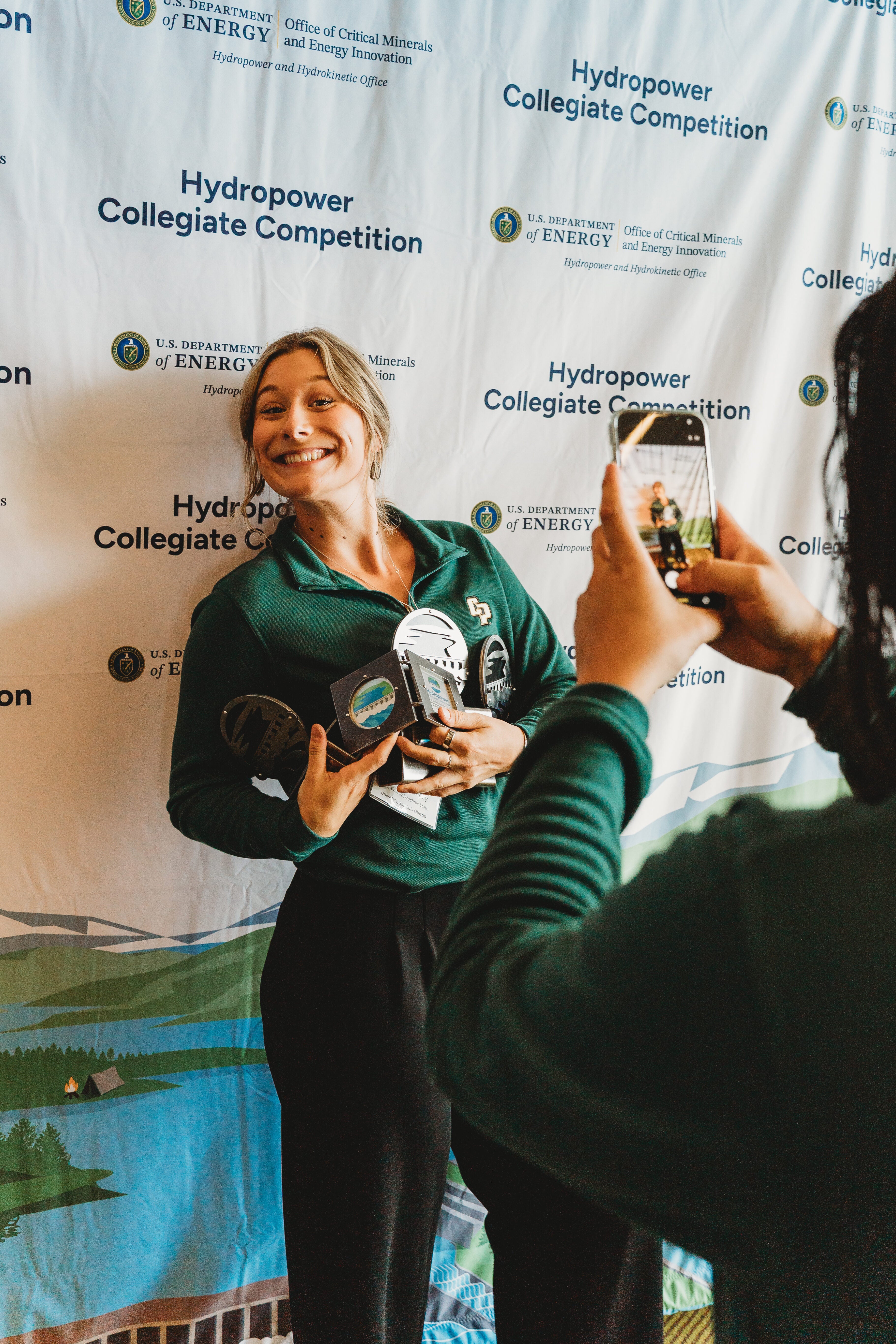 Student smiles holding an armful of awards