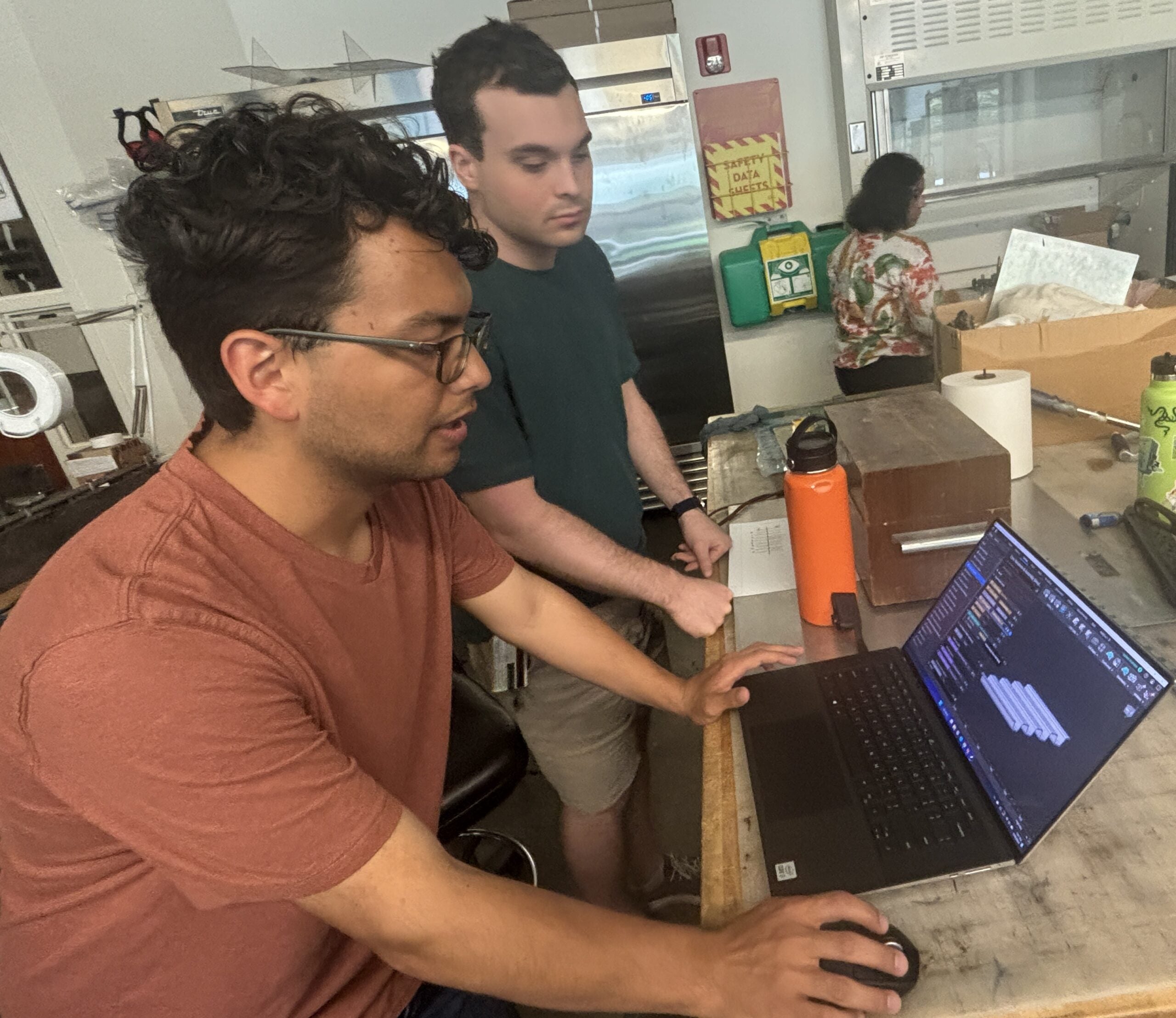 Two students look at a laptop screen as they design their material structure
