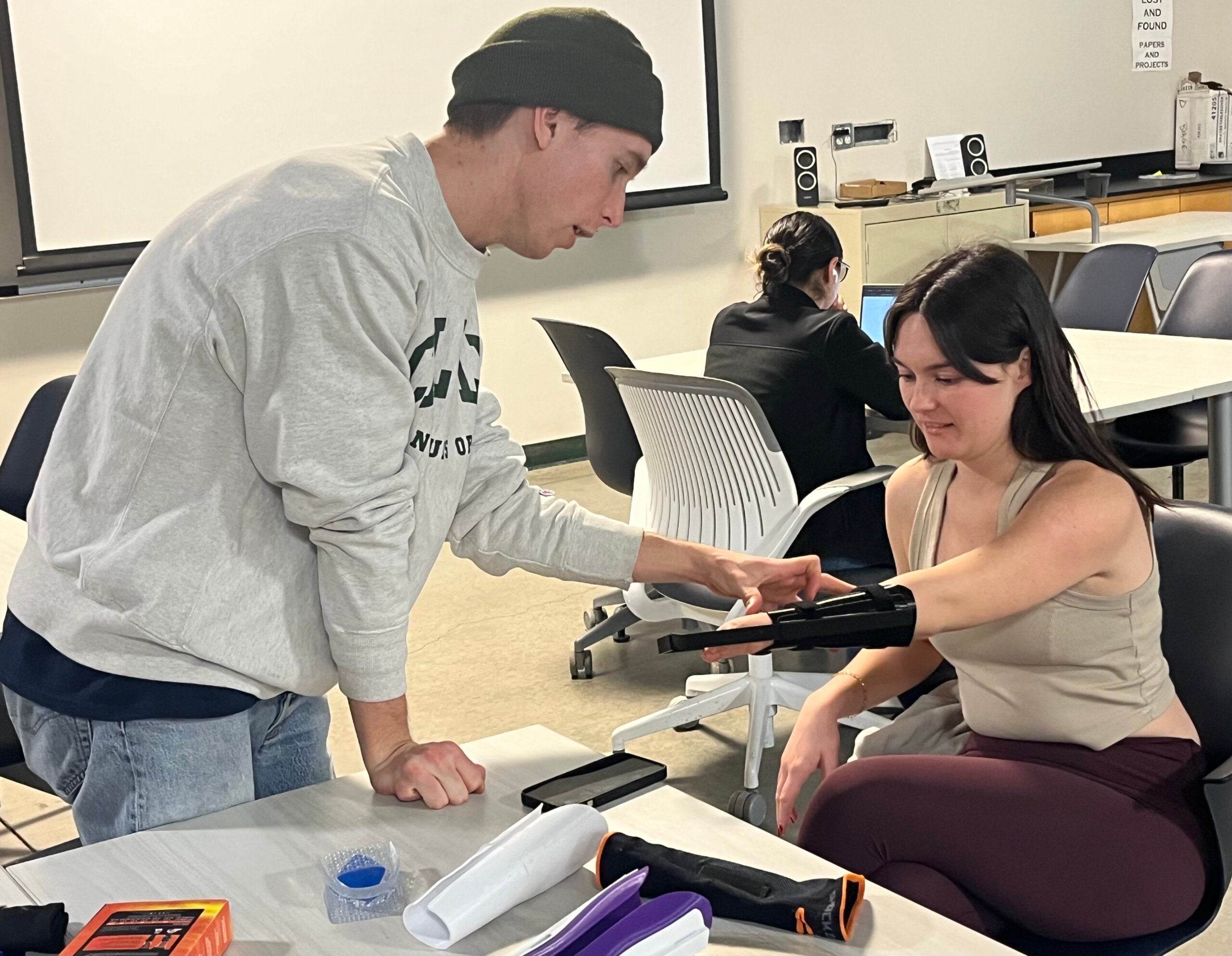 Student checks the fit of a prototype for a prosthetic aid for a student in the TECHE Lab