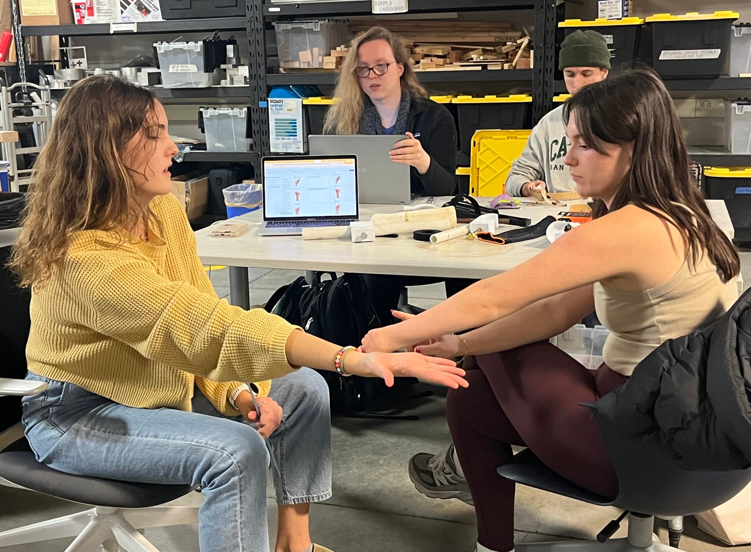 A senior project team discusses next steps for creating a prosthetic aid for a student who was born with her ulna and radius fused together