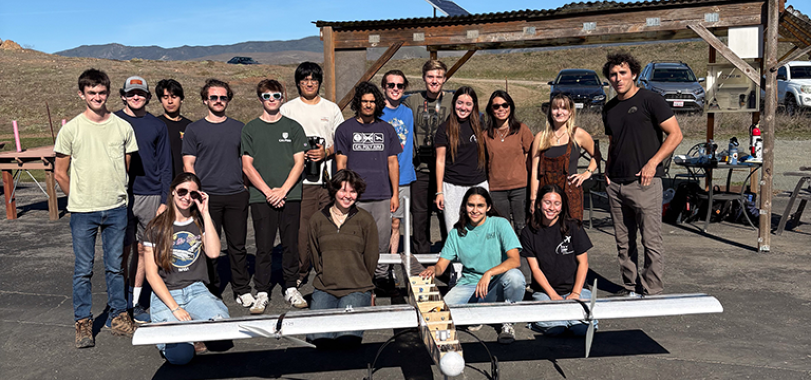 Members of club stand next to a prototype of their plane