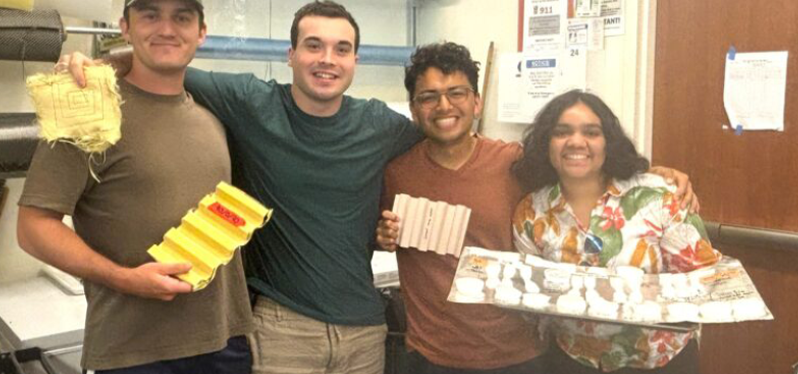 Four students pose in the Composites Lab with various materials