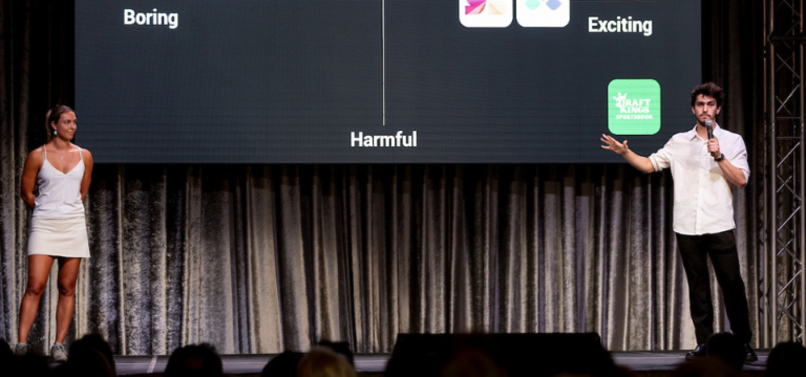 Two people standing on a stage presenting their project proposal to a crowd