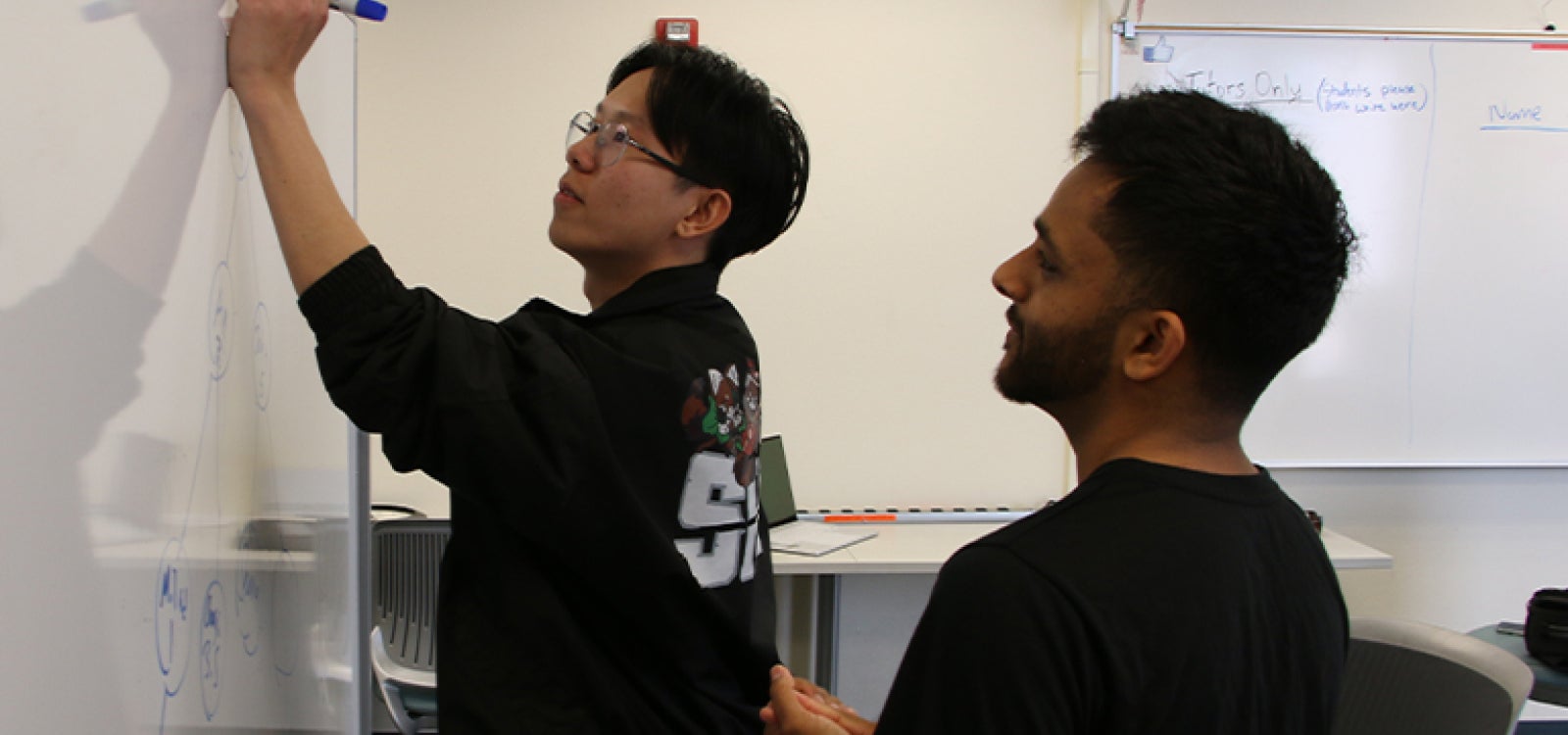 Tutors work out a problem-solving approach on the whiteboard