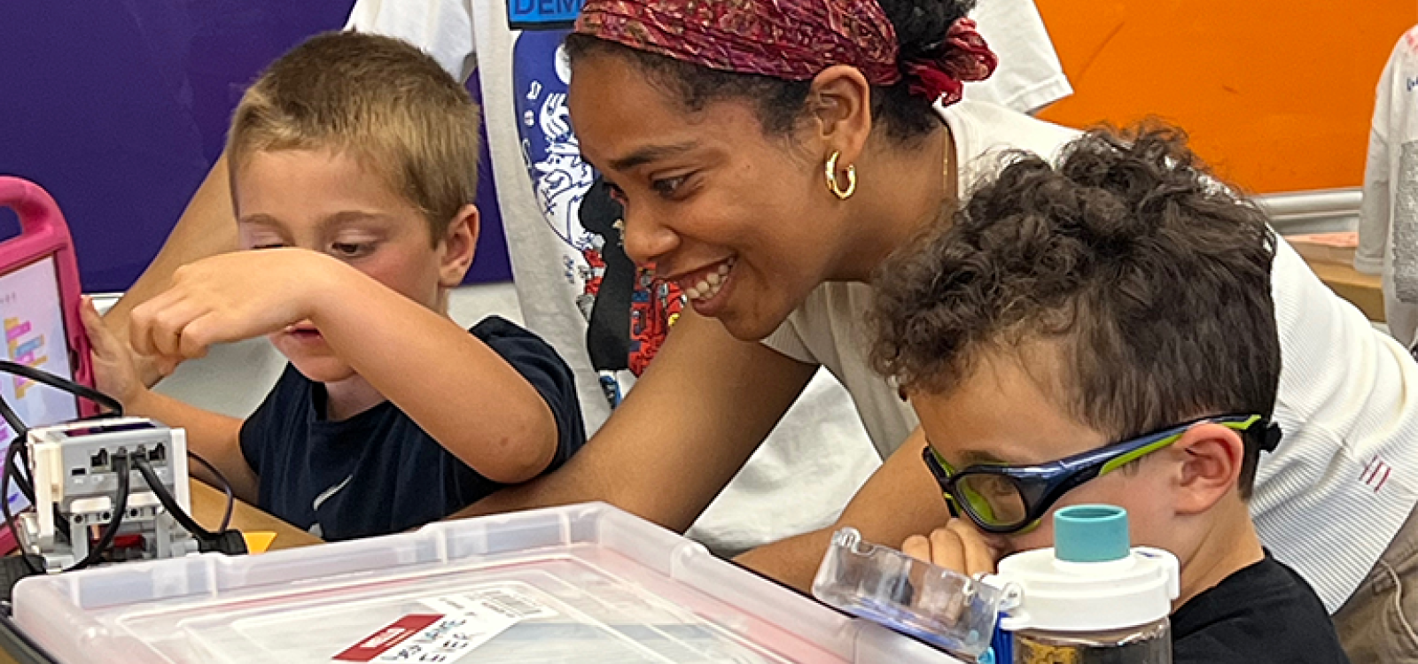 A woman helping two elementary school students with their projects