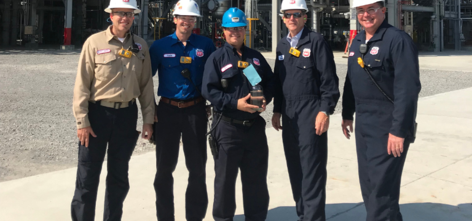 Five men with hard hats smiling at the camera.