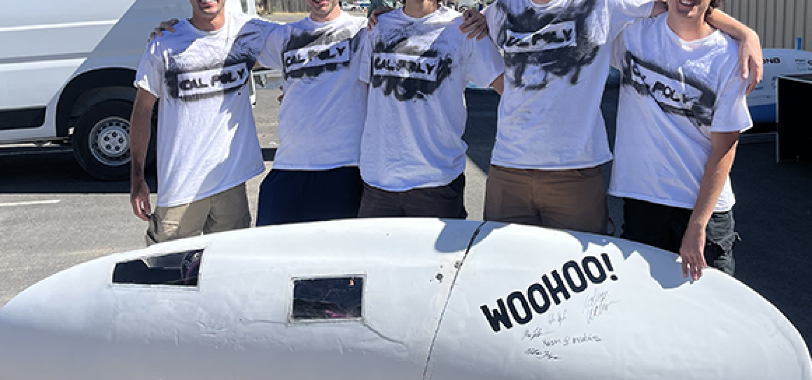 Students stand next to human-powered vehicle