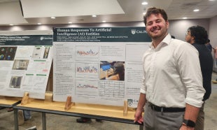 Student standing beside a research poster presentation during a campus symposium or academic showcase.